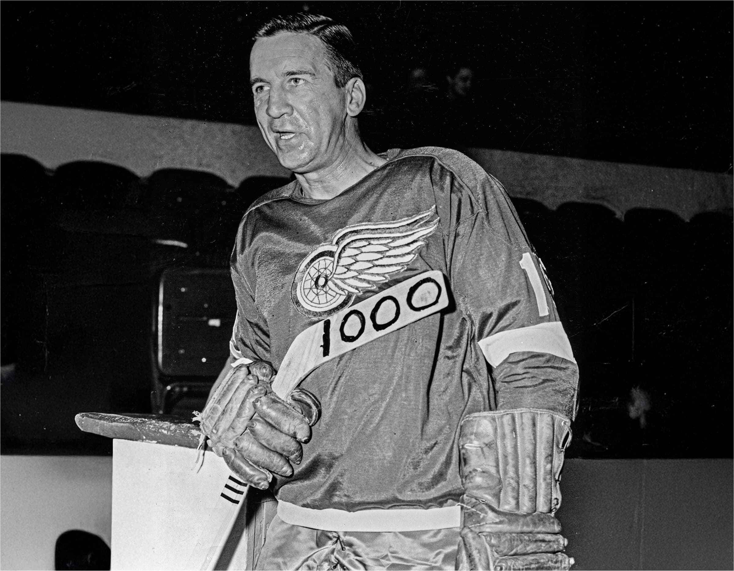 Ted Lindsay holding ice hockey stick with 1000 career games